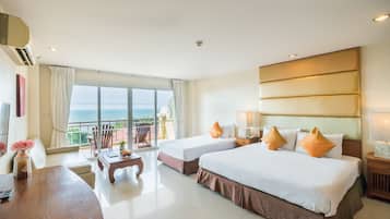 Habitación de hotel con dos camas, un escritorio, una silla y vista al océano.