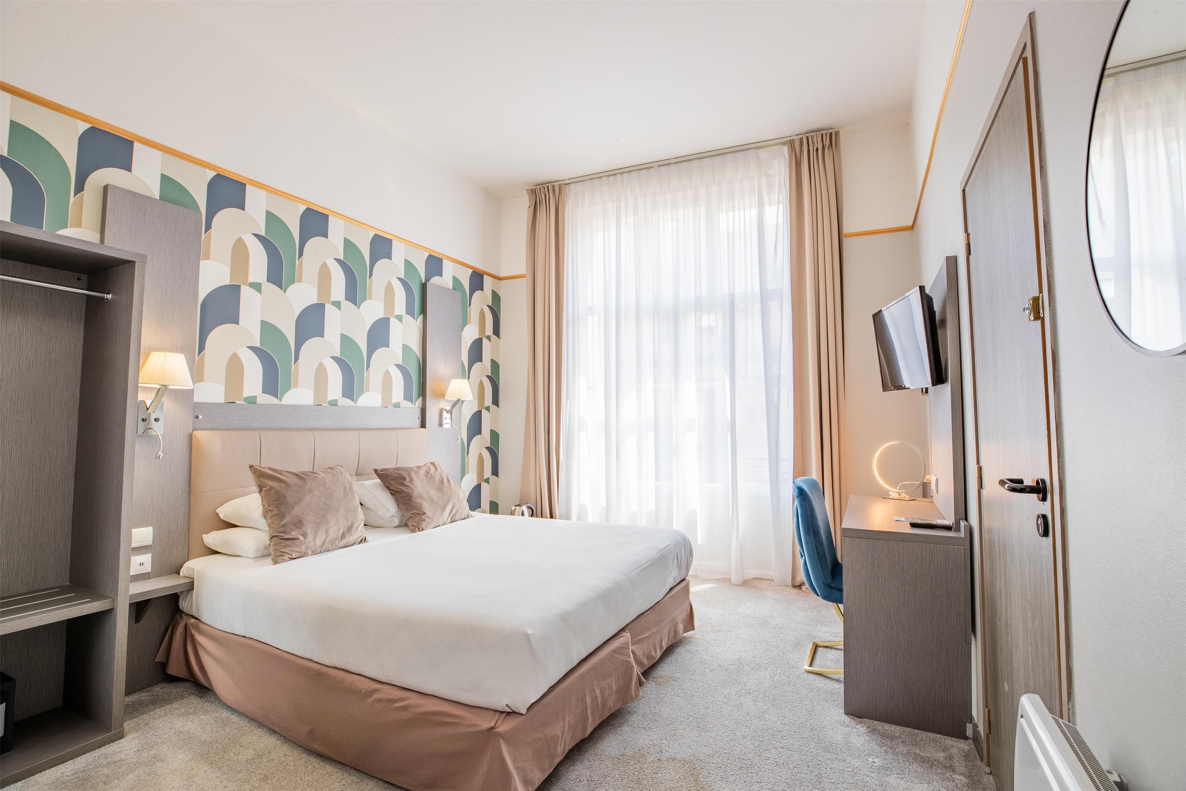 Una habitación de hotel con cama, escritorio, televisor y armario.
