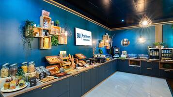 A hotel reception area with a blue wall, wooden shelves with plants, a Best Western sign, and a buffet with various food items.