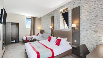 A hotel room with two beds, a desk, a TV, and a stone-textured wall.