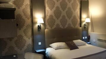 A hotel room with a large bed, two bedside lamps, a headboard, and a wall-mounted mirror.