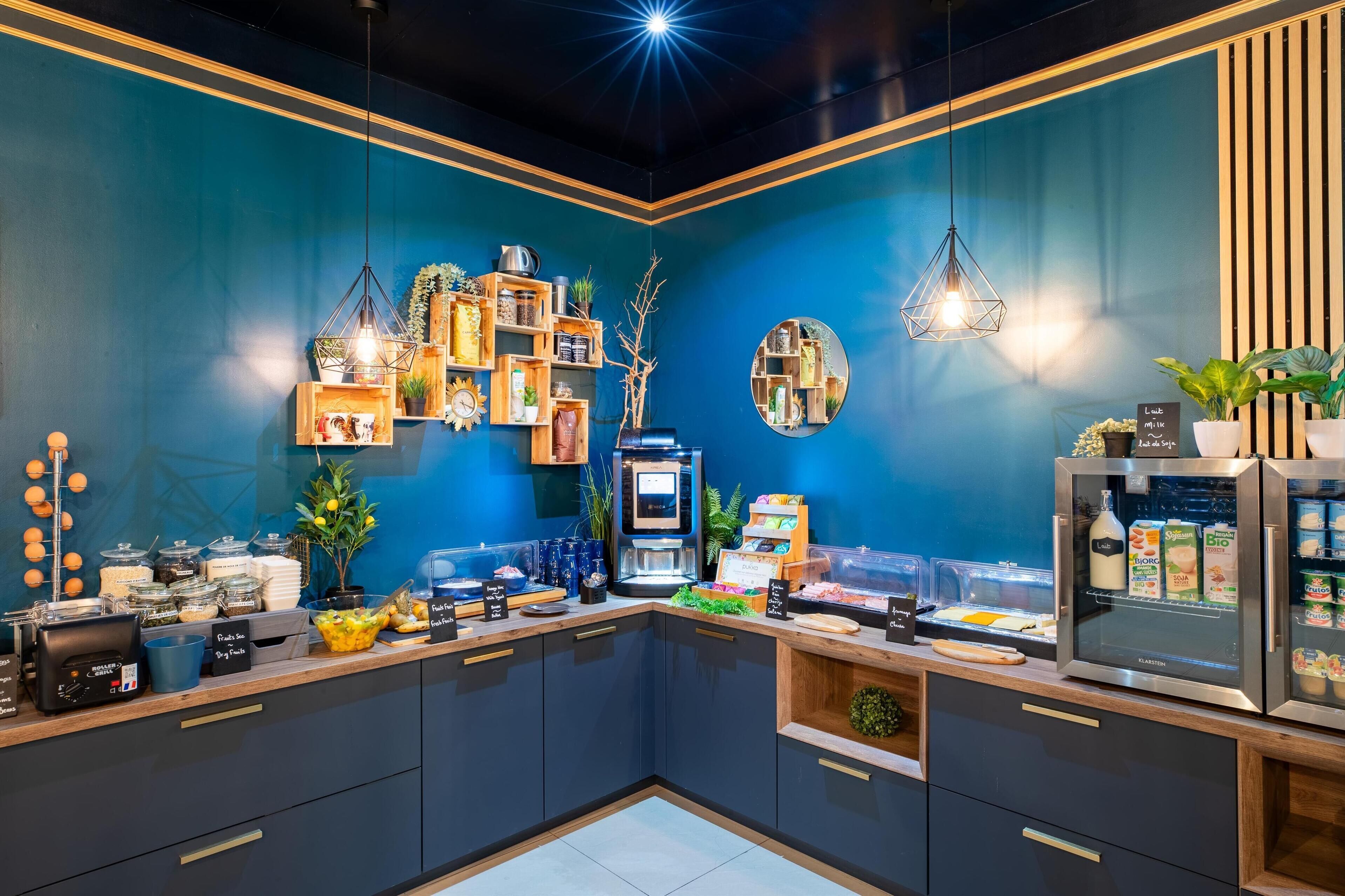 A modern kitchen with a blue accent wall, wooden cabinets, and various food items and appliances.