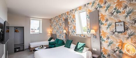 Habitación de hotel con una cama grande, dos camas más pequeñas, un escritorio, una silla, un armario y un espejo.