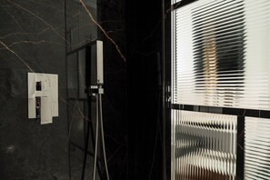 A modern bathroom with a black marble wall, a shower with a chrome faucet, and a window with blinds. - Hotel Helvetia Thermal Spa 4s (Alto Reno Terme)
