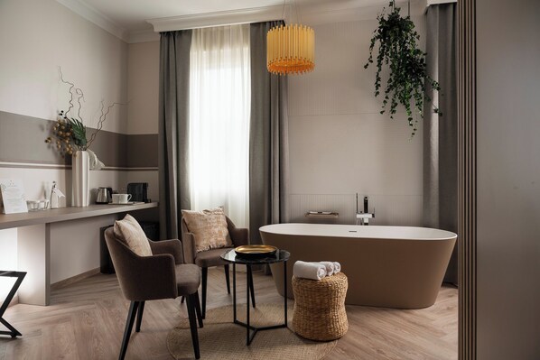 Un baño moderno con una bañera independiente, una mesa redonda con sillas y una planta colgante.