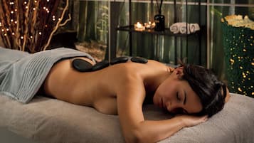 Une personne reçoit un massage du dos avec des pierres sur une table de massage dans un spa.