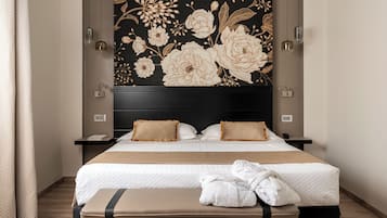Une chambre d'hôtel avec un grand lit, deux tables de chevet, une tête de lit recouverte d'un papier peint à motifs floraux et un peignoir posé sur le lit.