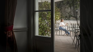 A person sitting at an outdoor table with a view of a stone wall and greenery. - Hotel Helvetia Thermal Spa 4s (Alto Reno Terme)