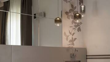 A modern bedroom with a large bed, a mirrored wardrobe, and pendant lights.