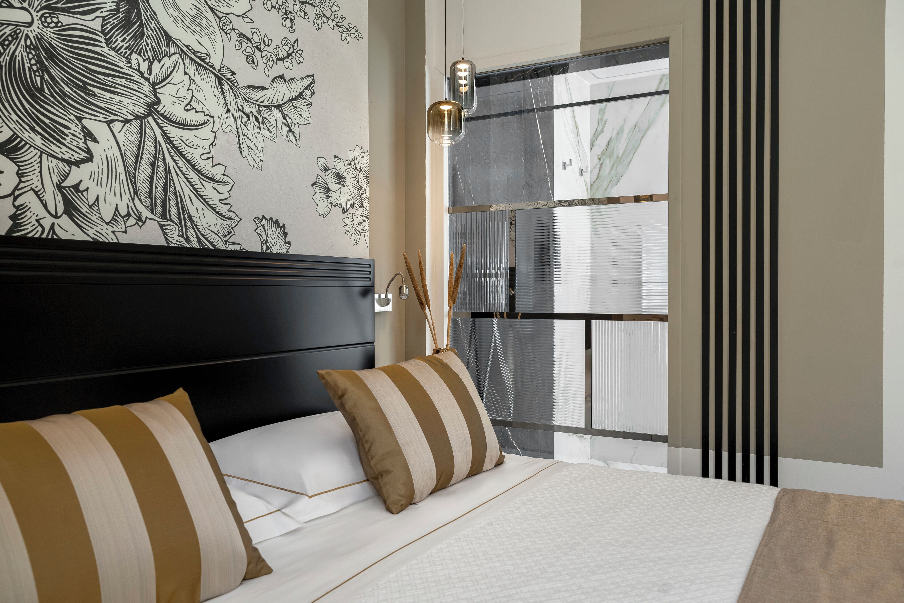 A bedroom with a large bed, striped pillows, a black headboard, a wall mural, and a window with blinds.