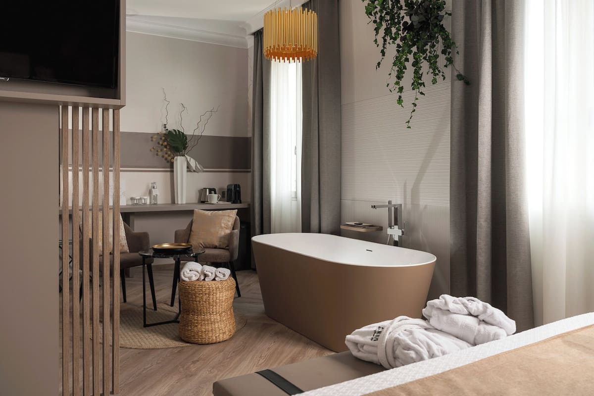 A modern bathroom with a freestanding bathtub, a wooden vanity, and a hanging plant.