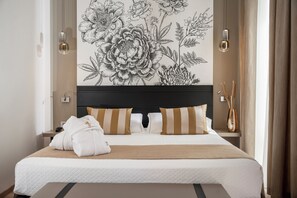 A neatly made bed with striped pillows and a beige throw blanket, a wall-mounted light fixture, and a decorative floral mural. - Hotel Helvetia Thermal Spa 4s (Alto Reno Terme)