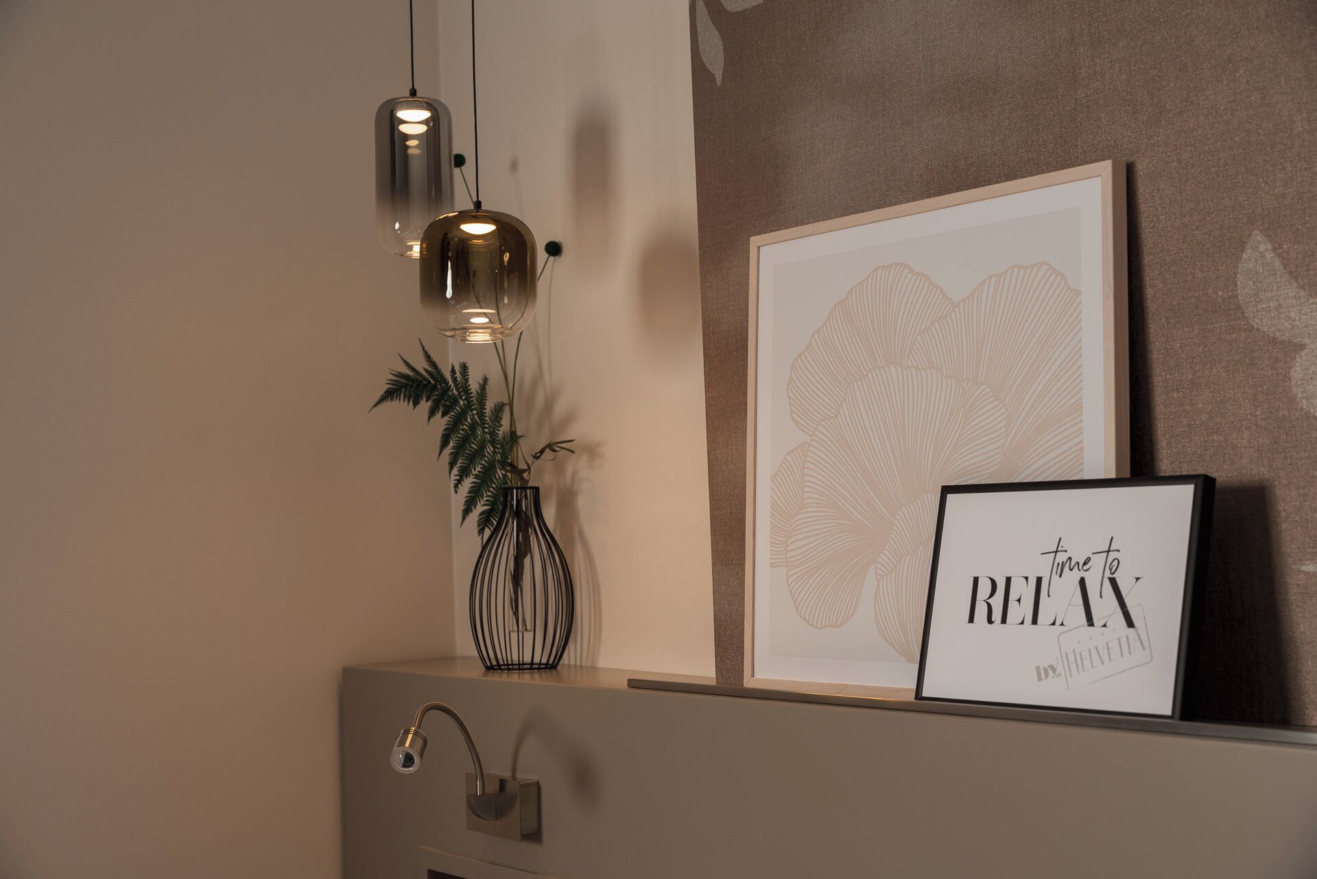 A wall-mounted shelf with a framed artwork, a potted plant, and a framed sign.