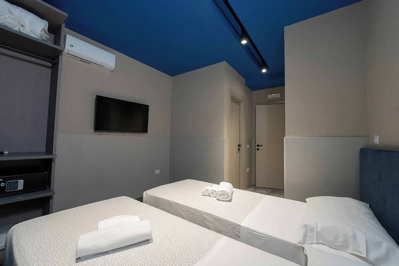 A hotel room with two beds, a TV, and a minibar.