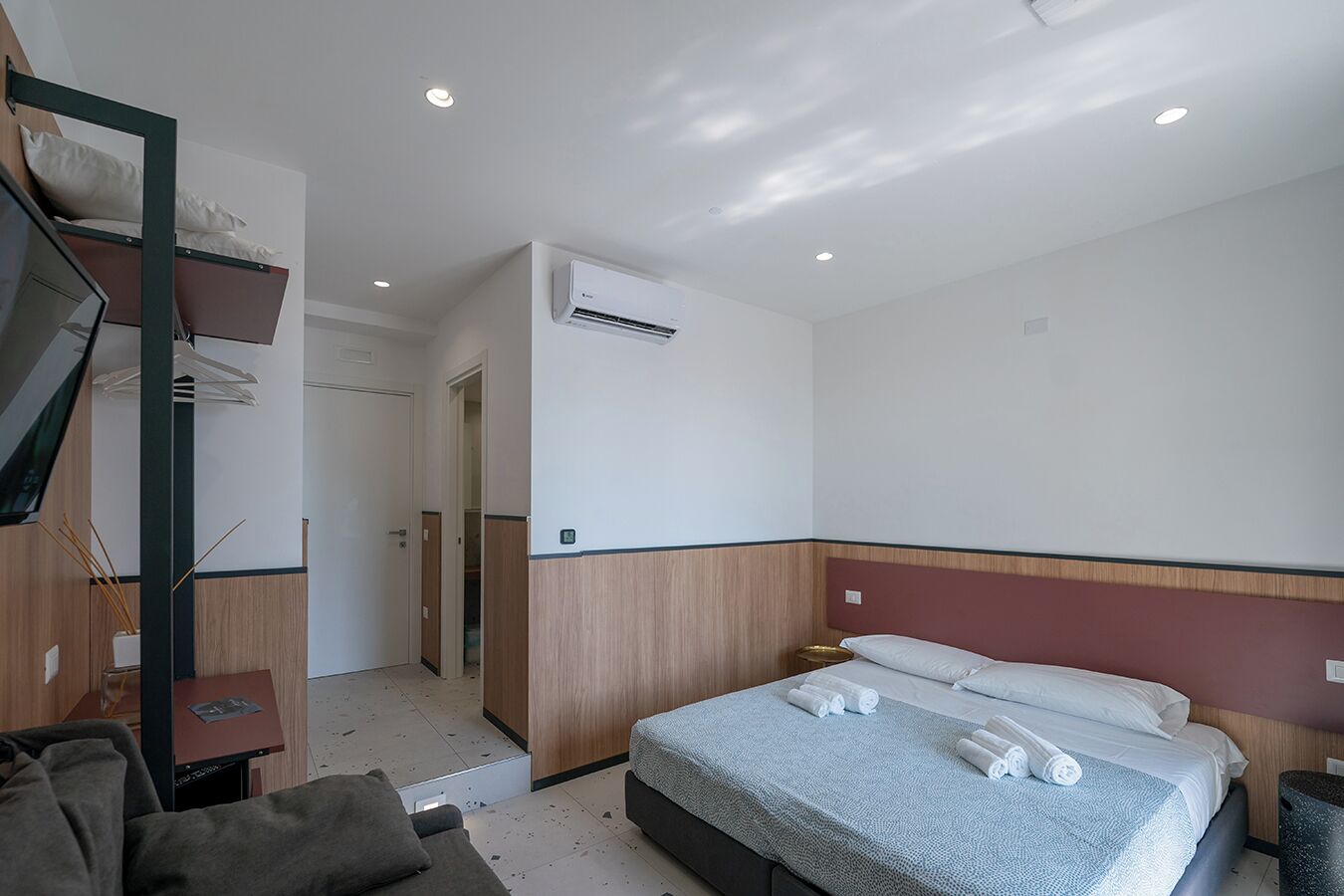 Une chambre d’hôtel équipée d’un lit, d’un bureau, d’une chaise, d’une armoire et d’un appareil de climatisation.