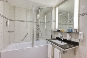 Un baño moderno con ducha envuelta en vidrio, una bañera blanca y un lavabo con encimera de granito.