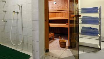 A bathroom with a shower, a wooden bench, and a glass shelf with towels.