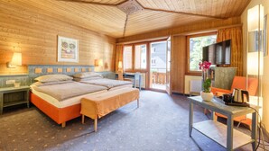 Una habitación de cabaña de madera con una cama, un escritorio, un televisor y una ventana.