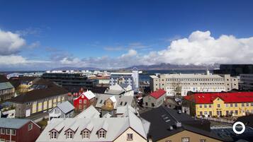 Un paysage urbain mêlant bâtiments modernes et traditionnels, avec une tour imposante et une vue sur des montagnes au loin.
