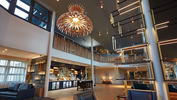 A spacious lobby with a high ceiling, a central seating area, and a modern bar. - Wychwood Park (Crewe)