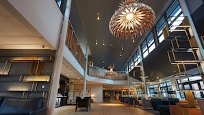 A spacious lobby with a high ceiling, modern lighting fixtures, and a central staircase. - Wychwood Park (Crewe)