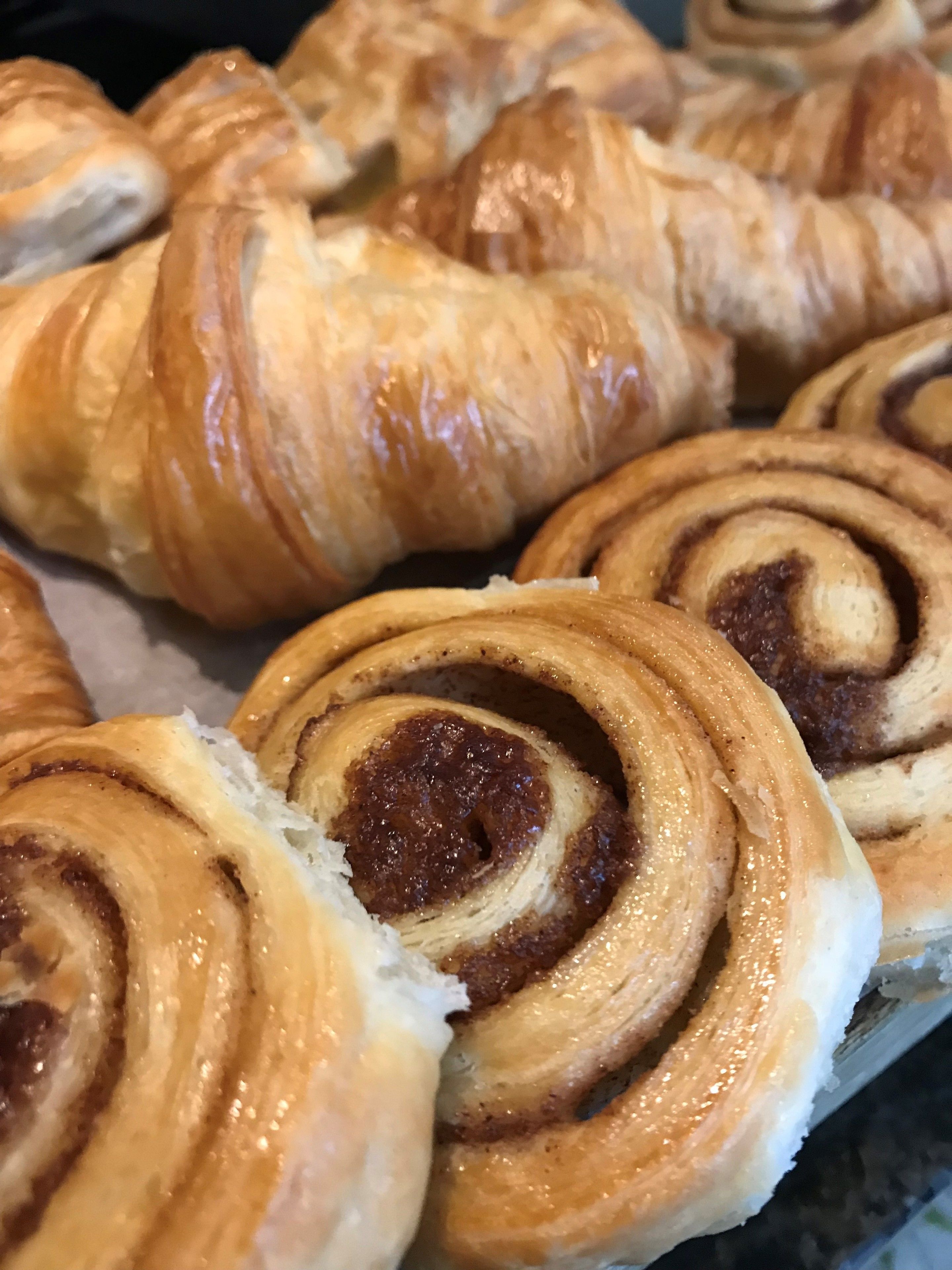 A tray of freshly baked pastries, including croissants and cinnamon rolls.