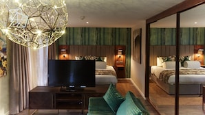 A modern hotel room with a large TV, a green sofa, and a unique spherical light fixture. - Wychwood Park (Crewe)