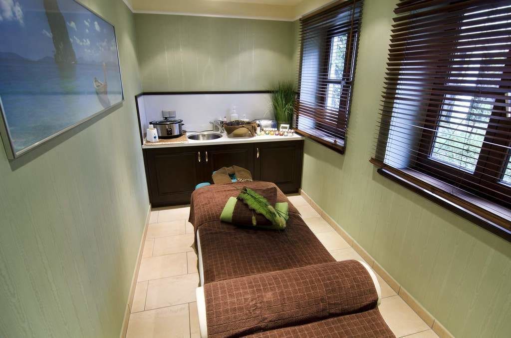 Una habitación compacta con cama, kitchenette pequeña y ventana con persianas.