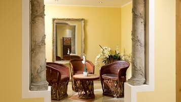 A room with a round table and four chairs, a large mirror, and a vase with white flowers.
