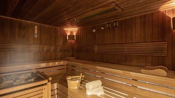 Eine Sauna mit Holzbänken, einem Eimer und Handtüchern.