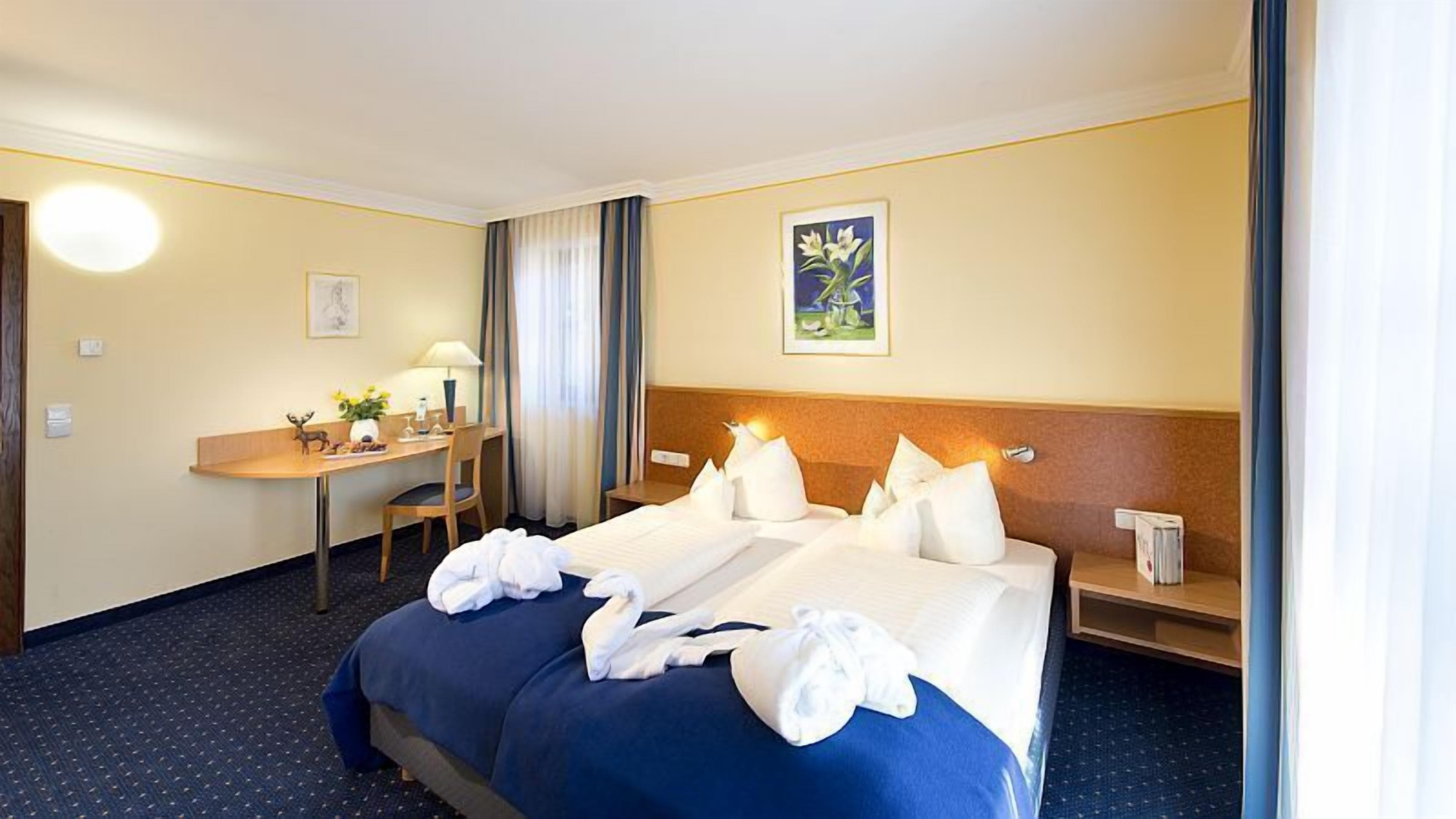A hotel room with a large bed, a desk, and a chair.