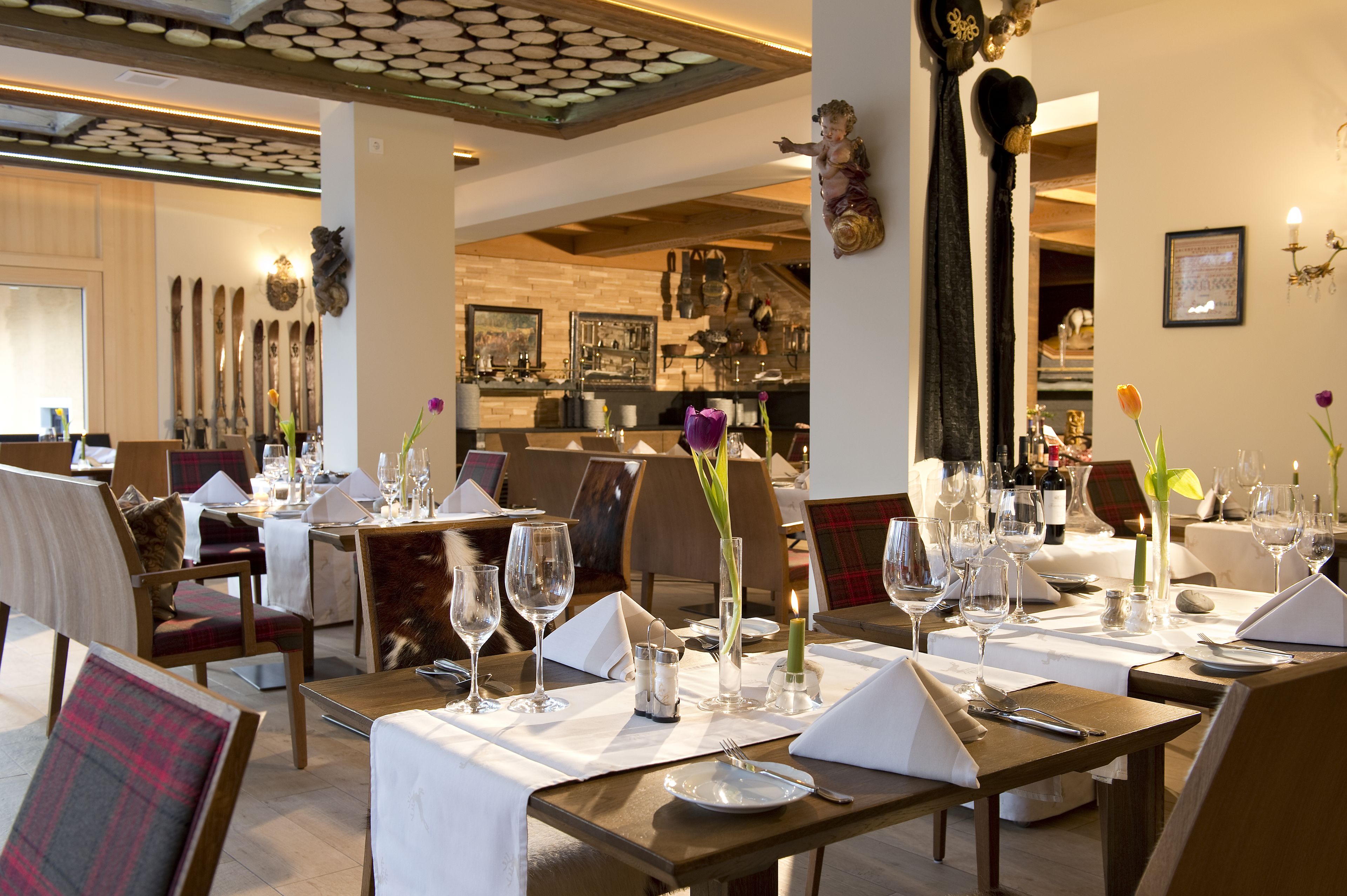 Un restaurante con mesas dispuestas para comer, que presenta un interior moderno con mobiliario de madera y detalles decorativos.
