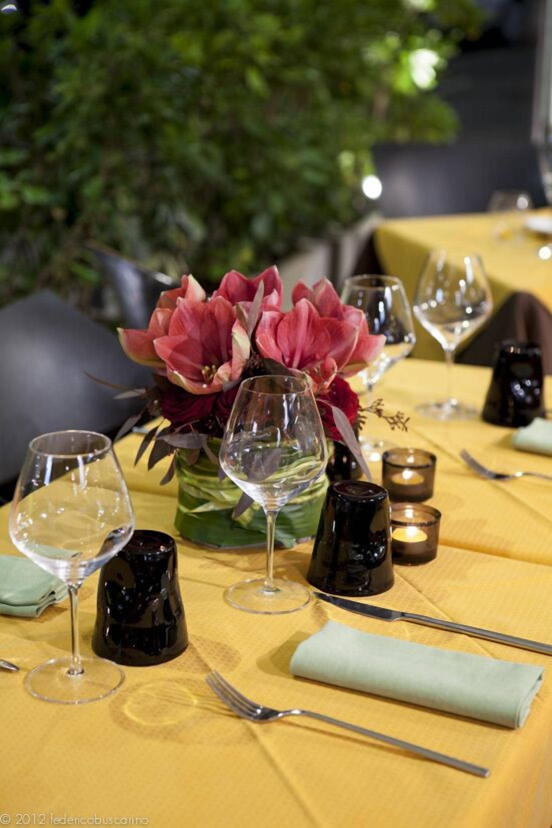 A table set with wine glasses, a vase with flowers, and candles.