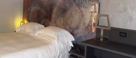 A modern hotel room with a large bed, a desk, and a unique abstract wall art piece.