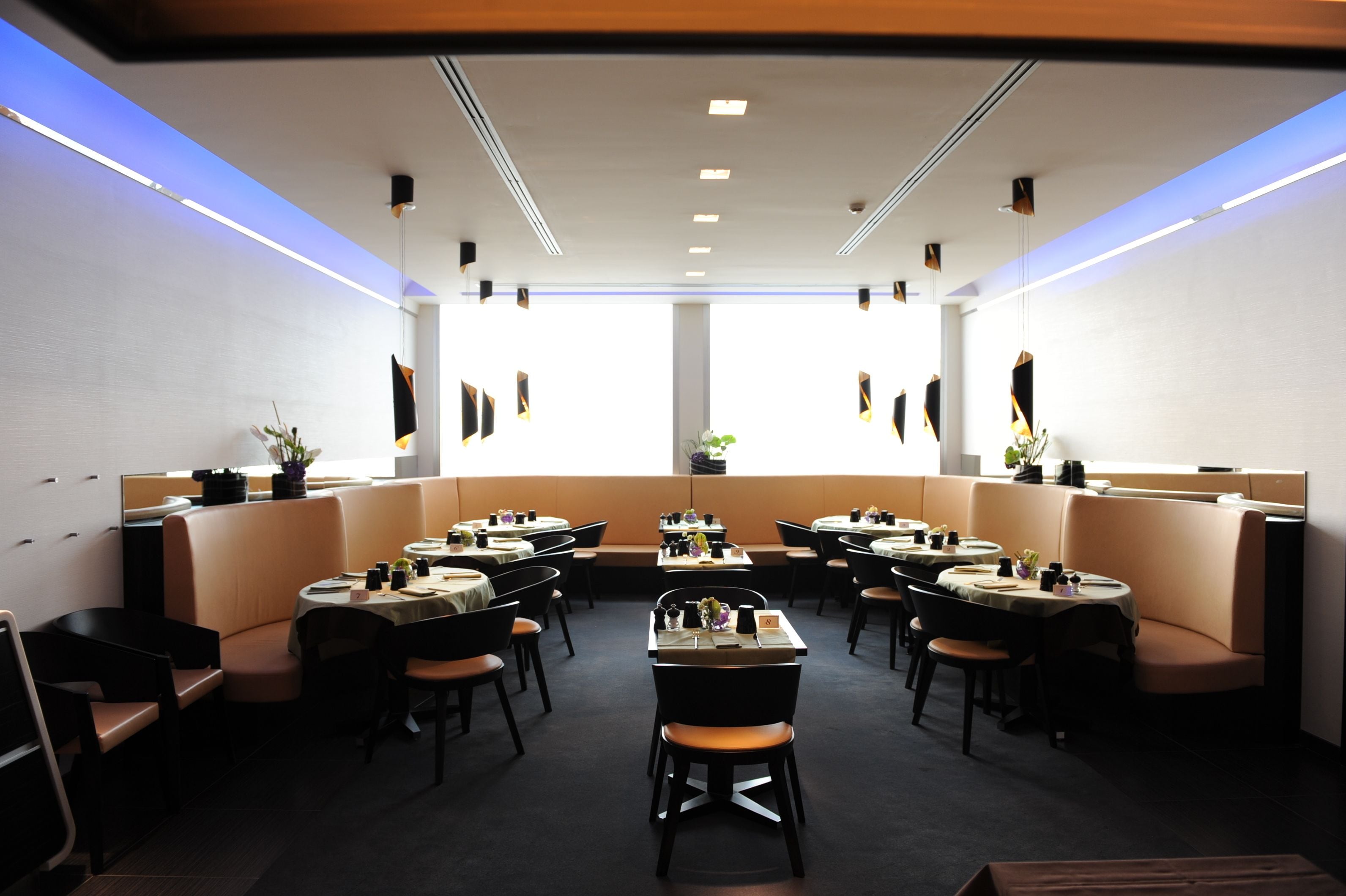 Een modern restaurant met zitbankjes en een grote eettafel in het midden.