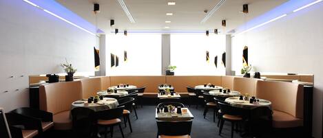 A modern restaurant with booth seating and a central dining table.