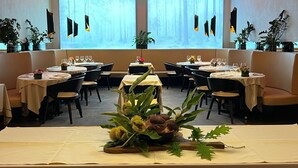 A restaurant with round tables, booths, and potted plants. - Arli Hotel Business and Wellness (Bergamo)