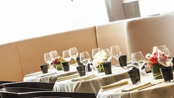 A dining area with tables set for service, chairs, and pendant lighting.