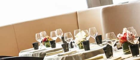 A dining area with tables set for service, chairs, and pendant lighting.