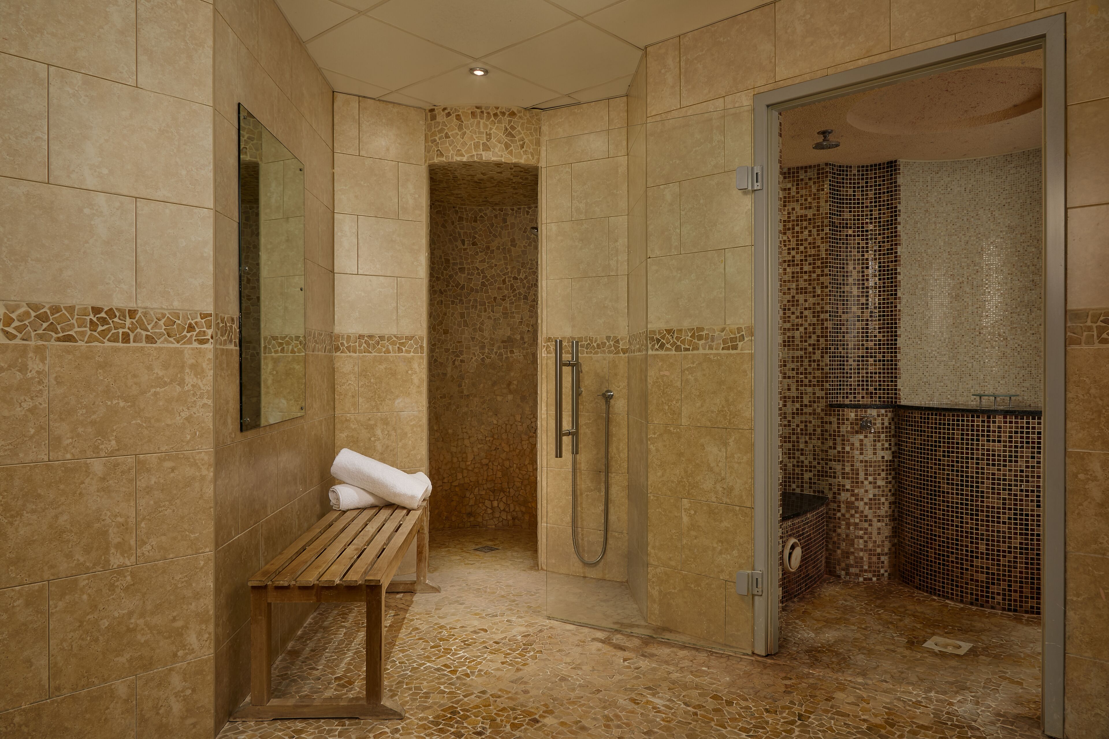 Ein Badezimmer mit Dusche, Sitzbank und Spiegel.