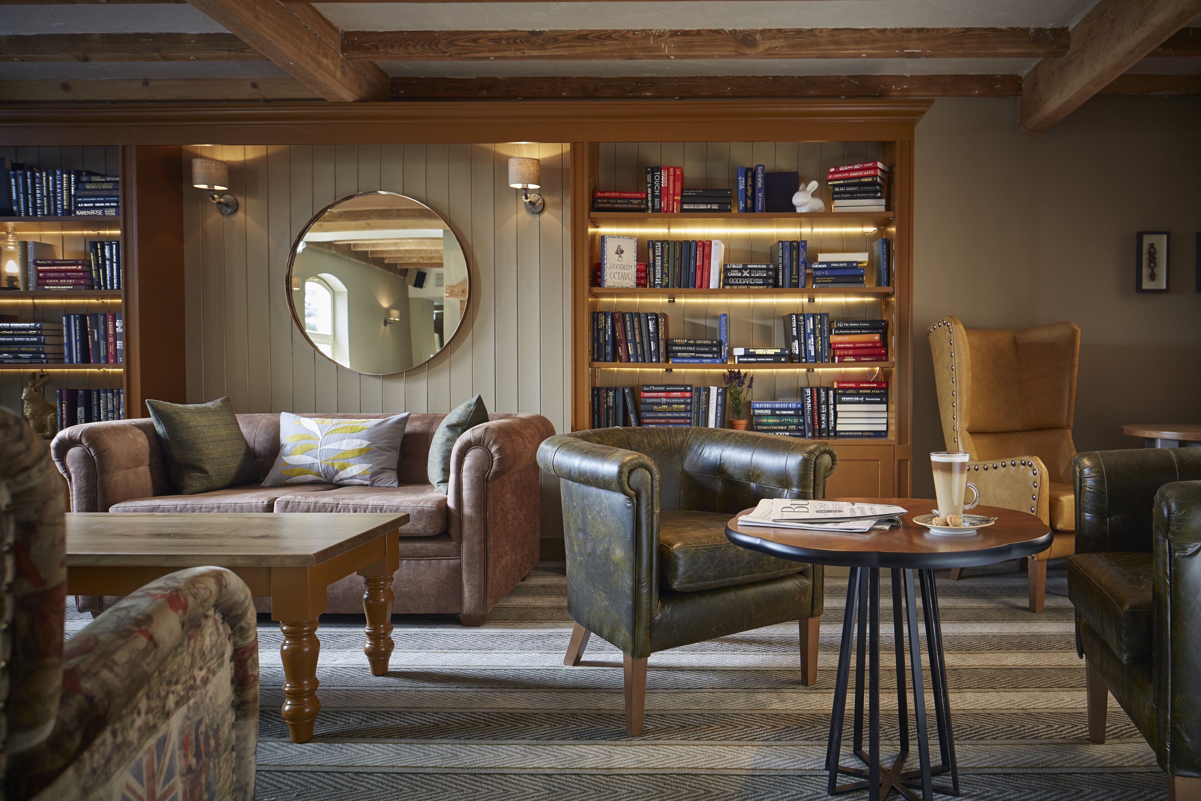 Una biblioteca acogedora con sillones de cuero, una mesa de centro de madera y estanterías llenas de libros.