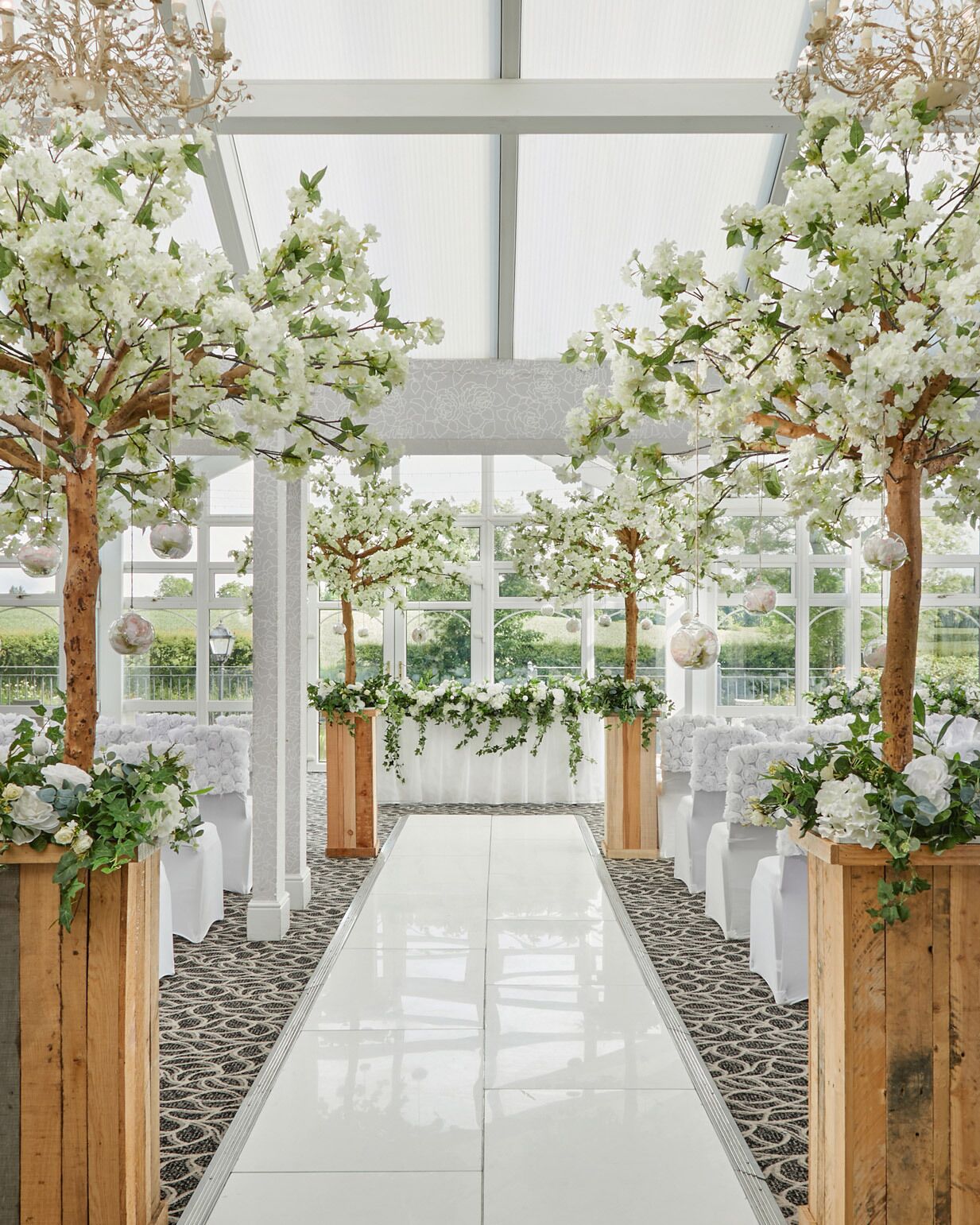Een binnenterrrein met een witte gangpad, houten tribunes met groen en zwevende glazen bollen.