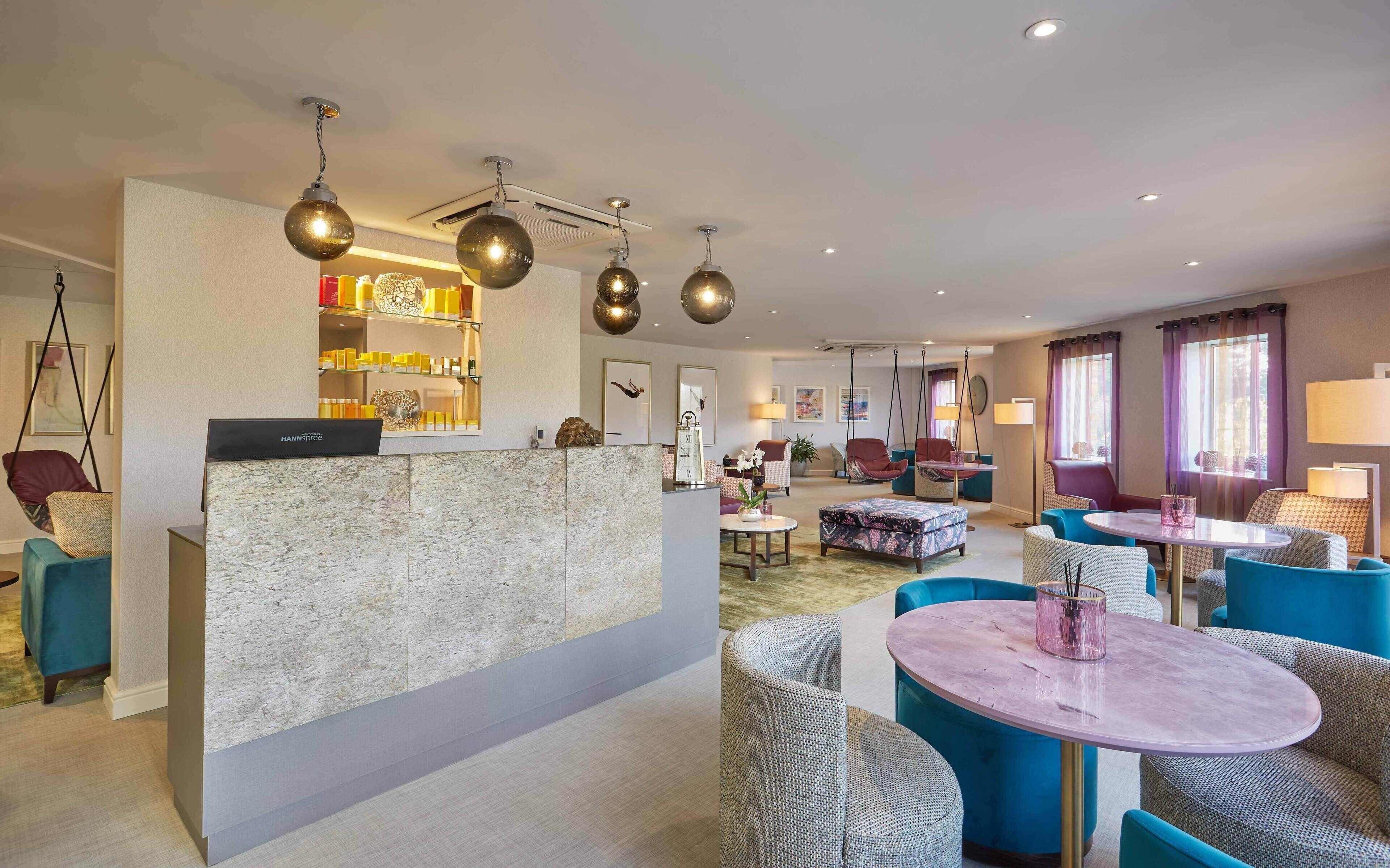 A hotel lobby with a reception desk, seating area, and hanging spherical light fixtures.