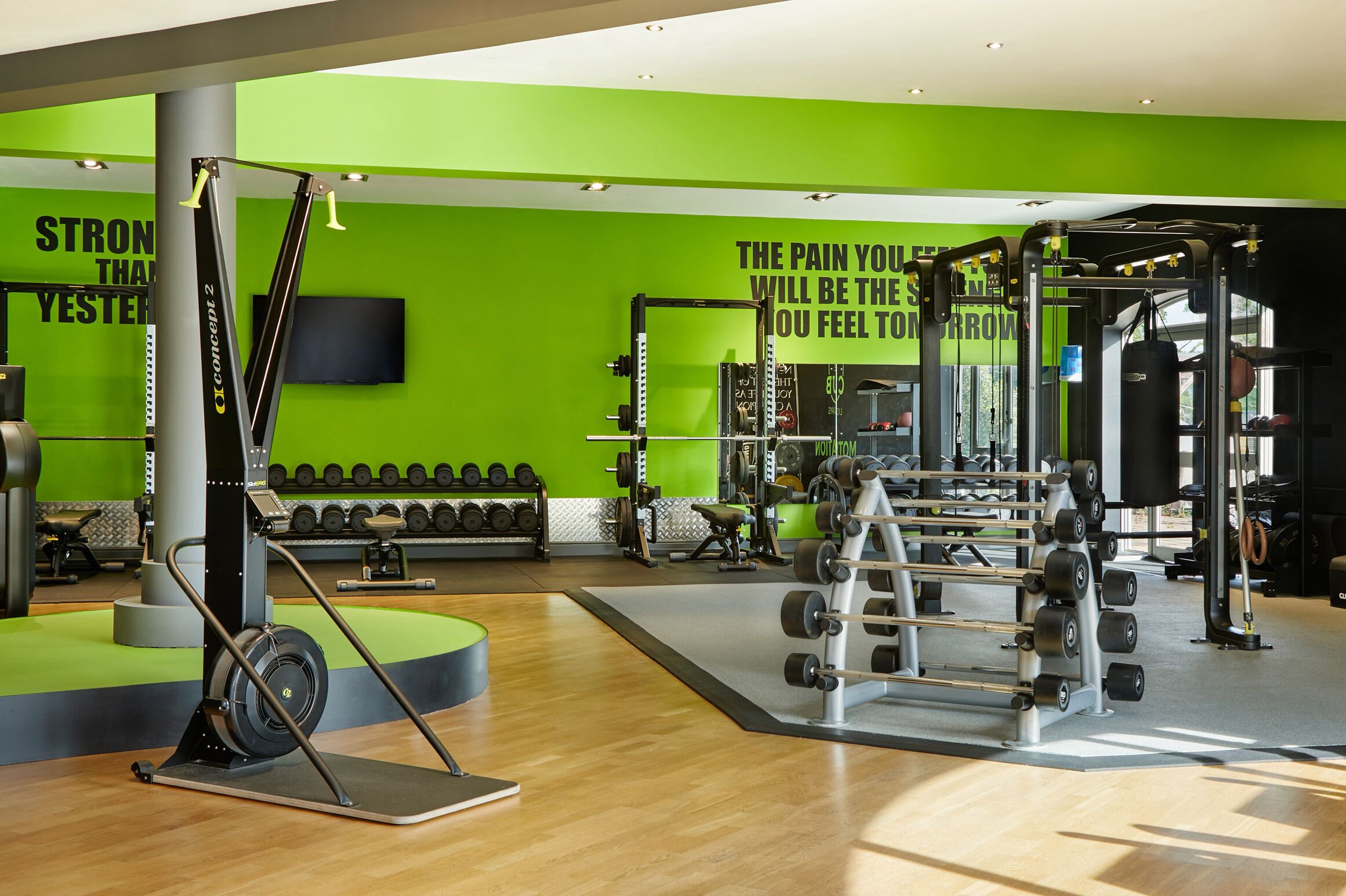 A gym with green walls, weightlifting equipment, and motivational quotes.