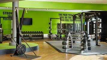 A gym with green walls, weightlifting equipment, and motivational quotes.