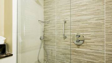 A modern shower with a glass door, a handheld showerhead, and a wall-mounted control panel.