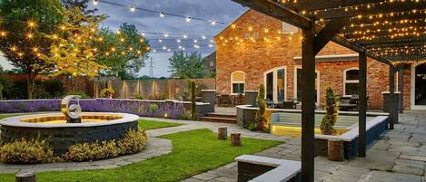 A patio area with a brick building, outdoor seating, and string lights.