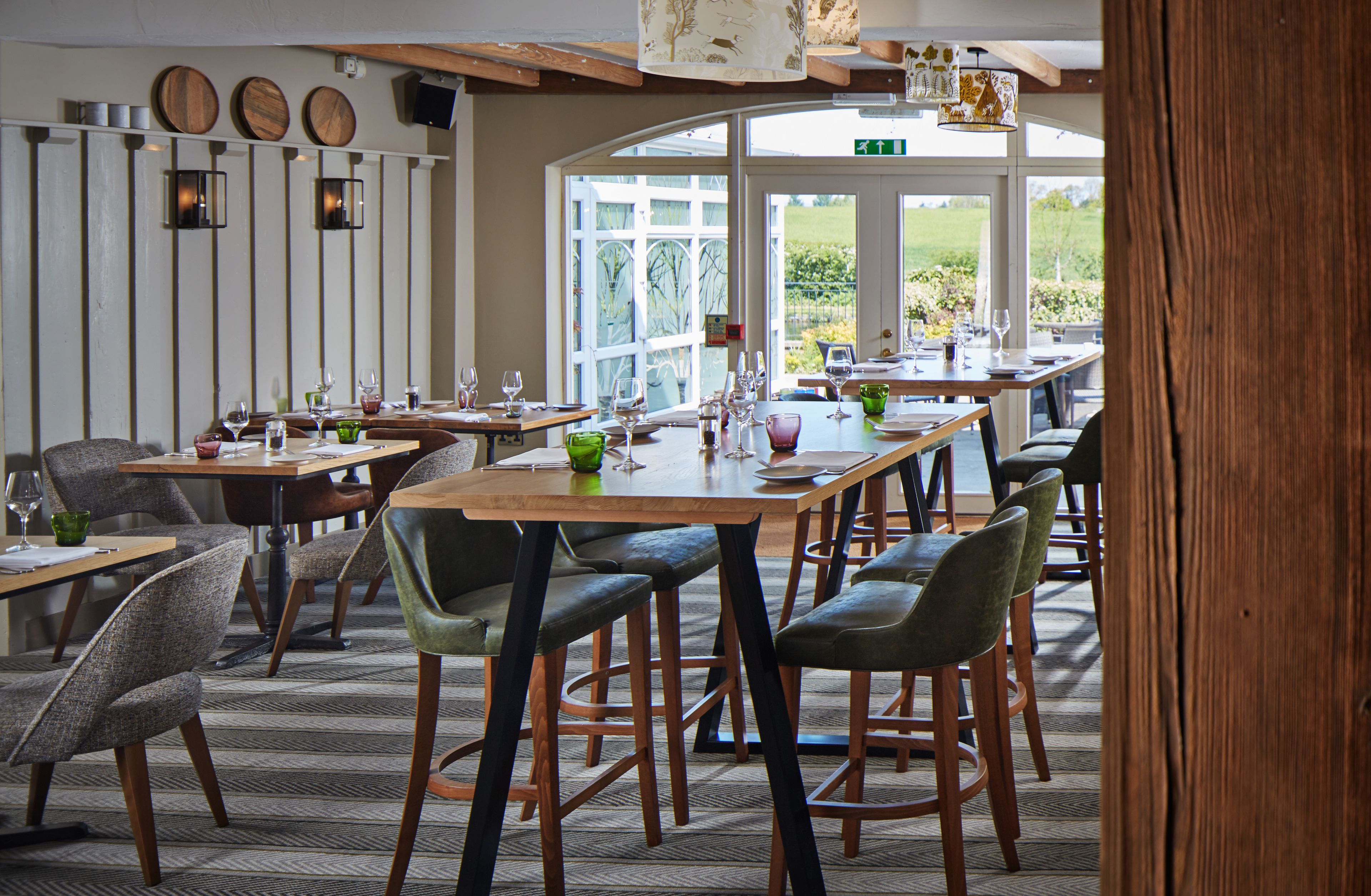 A restaurant with multiple tables and chairs, large windows, and a view of the outdoors.