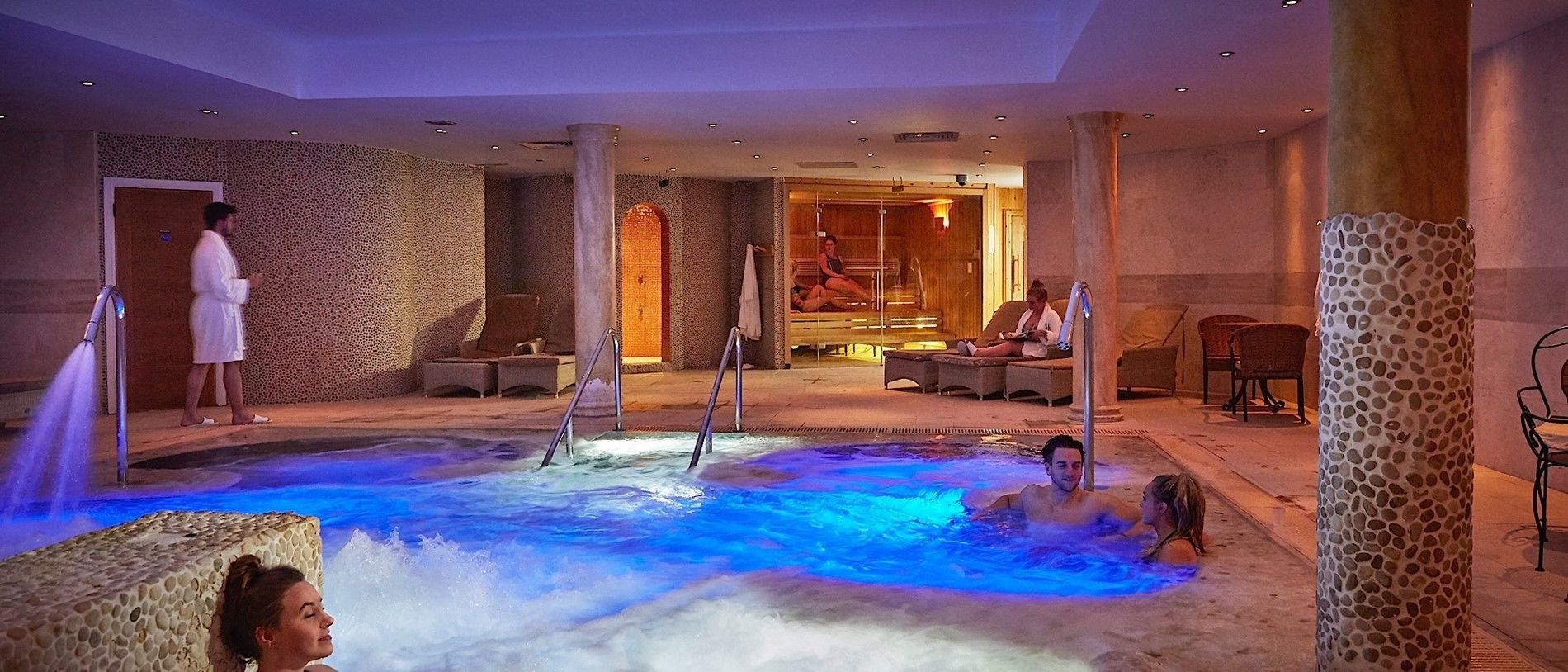 A spa area with a hot tub, seating, and a person in a robe.