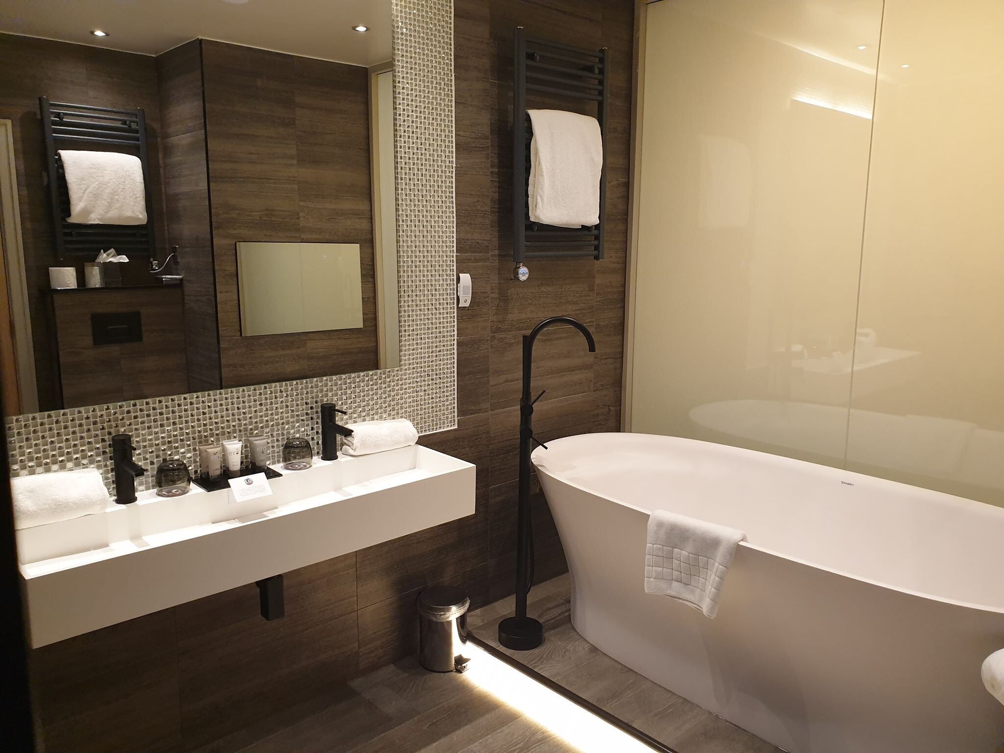 Ein modernes Badezimmer mit einer freistehenden Badewanne, einem großen Spiegel und einem Waschtisch mit mehreren Waschbecken.